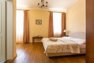 a bedroom with a bed and two windows at Hotel Slamič Ljubljana in Ljubljana