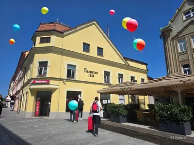 a group of people standing in front of a yellow building with balloons at Apartments Fazarinc with parking, wellness and city store in the center of Celje in Celje