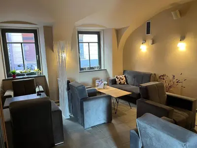 a waiting room with couches and a table and windows at Cukrarna Guest Accommodation in Kranj