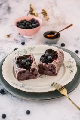 two pieces of blueberry cake on a plate with a fork at Cukrarna Guest Accommodation in Kranj