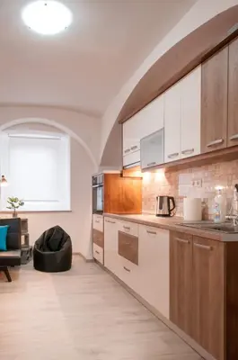 a kitchen with white cabinets and a couch in a room at The Maze Apartment in Ljubljana