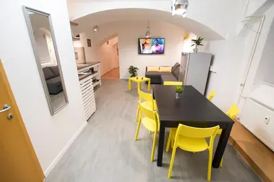 a kitchen and dining room with a black table and yellow chairs at The Maze Apartment in Ljubljana