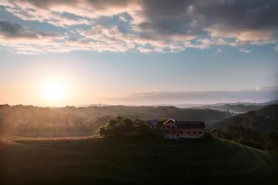 a house in a field with the sunset in the background at Hisa Vina in Podlehnik