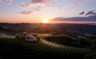 a house in a field with the sunset in the background at Hisa Vina in Podlehnik