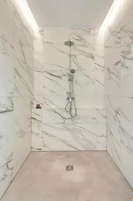 a bathroom with a shower with white marble walls at Pekarna apartments in Ljubljana