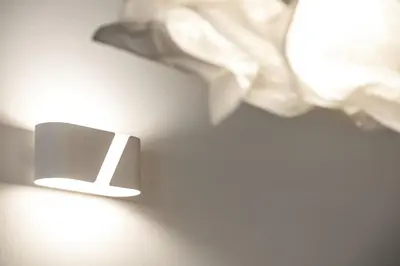 a light on a table next to a bed at Pekarna apartments in Ljubljana