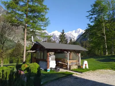a small house in a field with mountains in the background at House Berdnik in Stahovica