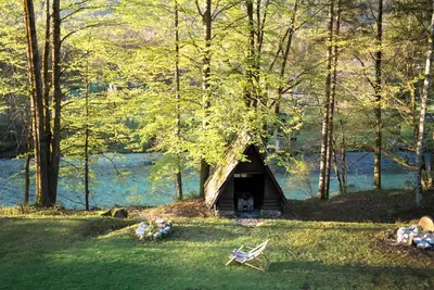 a small house in the middle of a field with a bench at TUBA Apartments in Bohinj