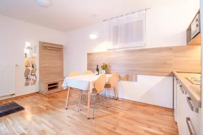 a kitchen and dining room with a white table and chairs at Alp Apartma in Radovljica