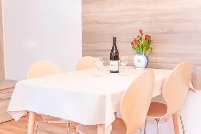 a white table with two glasses of wine and flowers at Alp Apartma in Radovljica