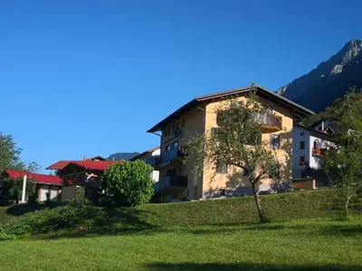 a building on a hill with a tree in front of it at Apartma Logar in Kobarid