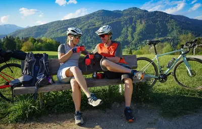 two people sitting on a bench with a bike at Hike & Bike Chalet in Bohinj