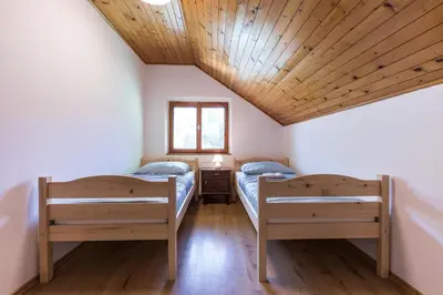 two beds in a room with a wooden ceiling at Dolar Rooms in Bled