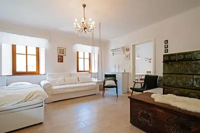 a bedroom with a bed and a living room with a chandelier at Pr`Mružo apartmaji in Bohinj