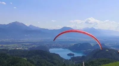 a red parachute flying in the air over a lake at Apartmaji Volf in Zgornje Gorje