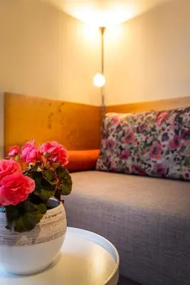 a vase with flowers on a table next to a bed at Apartmaji Volf in Zgornje Gorje