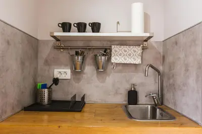 a kitchen with a sink and a shelf with cups at Apartma Lilly in Bled