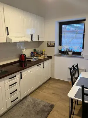 a kitchen with white cabinets and a table and a window at Alpino in Ljubljana