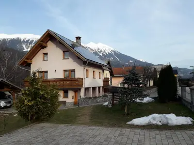 a house with a snow covered mountain in the background at Apartma Marjetica II. in Blejska Dobrava