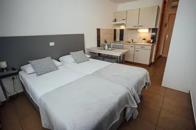 a bedroom with a large white bed and a kitchen at Sobe Rooms Nataly in Sežana