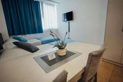 a room with a desk with a bed and a table with flowers at Sobe Rooms Nataly in Sežana