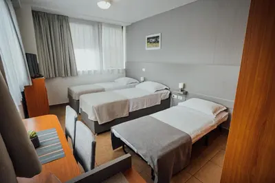 a hotel room with three beds and a table at Sobe Rooms Nataly in Sežana