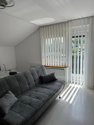 a living room with a couch and a large window at Apartments and Wellness Ščavničar in Ljutomer