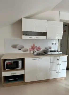 a kitchen with white cabinets and a counter with a microwave at Apartments and Wellness Ščavničar in Ljutomer