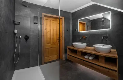 a bathroom with two sinks and a shower and a mirror at Vila Grad Bled - Sauna & Hot tub in Bled