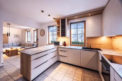 a kitchen with white cabinets and a living room at Vila Grad Bled - Sauna & Hot tub in Bled