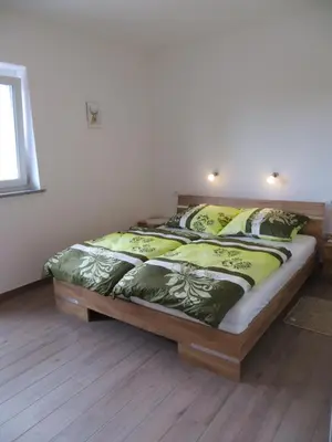 a bedroom with a bed with green and yellow sheets at Apartments and Wellness Jelovca in Radovljica