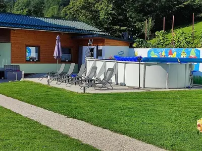 a pool with chairs and a table and a house at Apartments and Wellness Jelovca in Radovljica