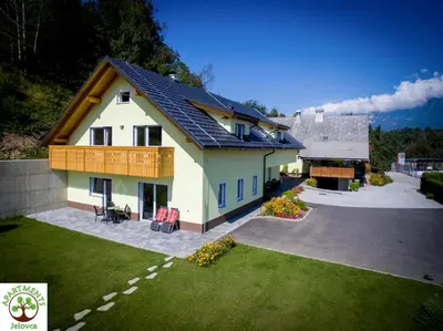 a white house with a balcony and a yard at Apartments and Wellness Jelovca in Radovljica