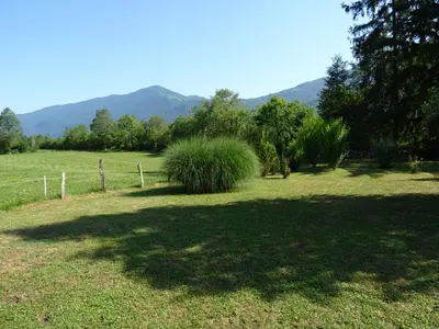 a large grass field with a fence and a tree at Soča House in Kobarid