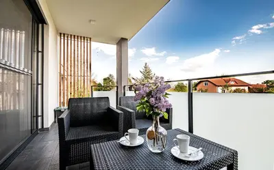 a table with two chairs and a vase of flowers on a balcony at Apartmaji BANONIA 