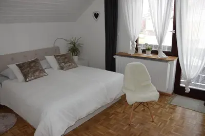 a bedroom with a white bed and a white chair at Studio Tara with balcony in Bled