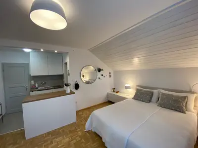 a bedroom with a white bed and a kitchen at Studio Tara with balcony in Bled
