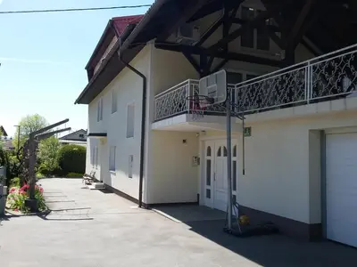 a white building with a balcony and a garage at Vila Bbq in Ljubljana