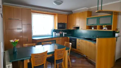 a kitchen with wooden cabinets and a table and chairs at Vila Bbq in Ljubljana