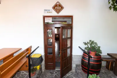 a door to a restaurant with a barrel next to it at Penzion Na Hribu in Slap