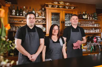 a group of three people standing in a bar at Guesthouse Tulipan in Lesce