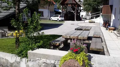 a wooden bench with flowers on the side of a street at Apartments & Hostel Bohinj in Bohinj