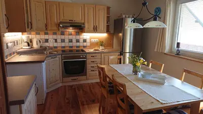 a kitchen with a wooden table and a counter top at Apartments Na Vasi in Bohinj