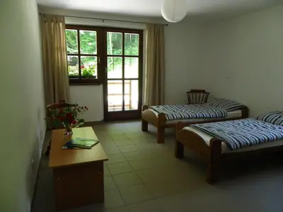 a room with two beds and a table and windows at The Millhouse Bled in Bled