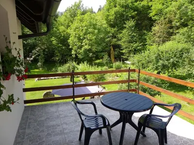 a table and chairs on a patio with a view of a garden at The Millhouse Bled in Bled