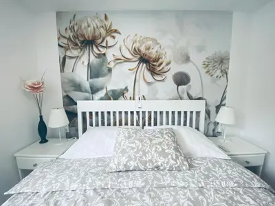 a bedroom with a white bed with flowers on the wall at Garden Paradise Bled Apartments - garden, pond and castle view in Bled