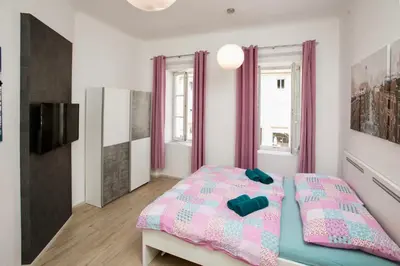 a bedroom with a pink and blue bed and a tv at Apartment Optim in Ljubljana