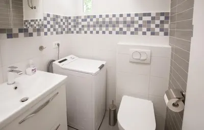a white bathroom with a toilet and a sink at Apartment Optim in Ljubljana