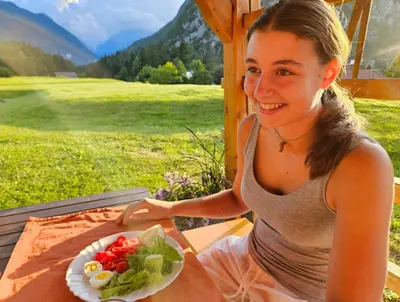 a woman sitting at a table with a plate of salad at Apartma Stenar in Mojstrana