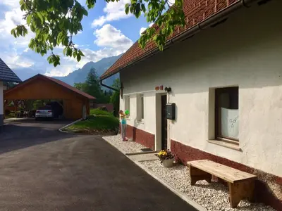 a bench sitting outside of a building with a house at Apartma Stenar in Mojstrana